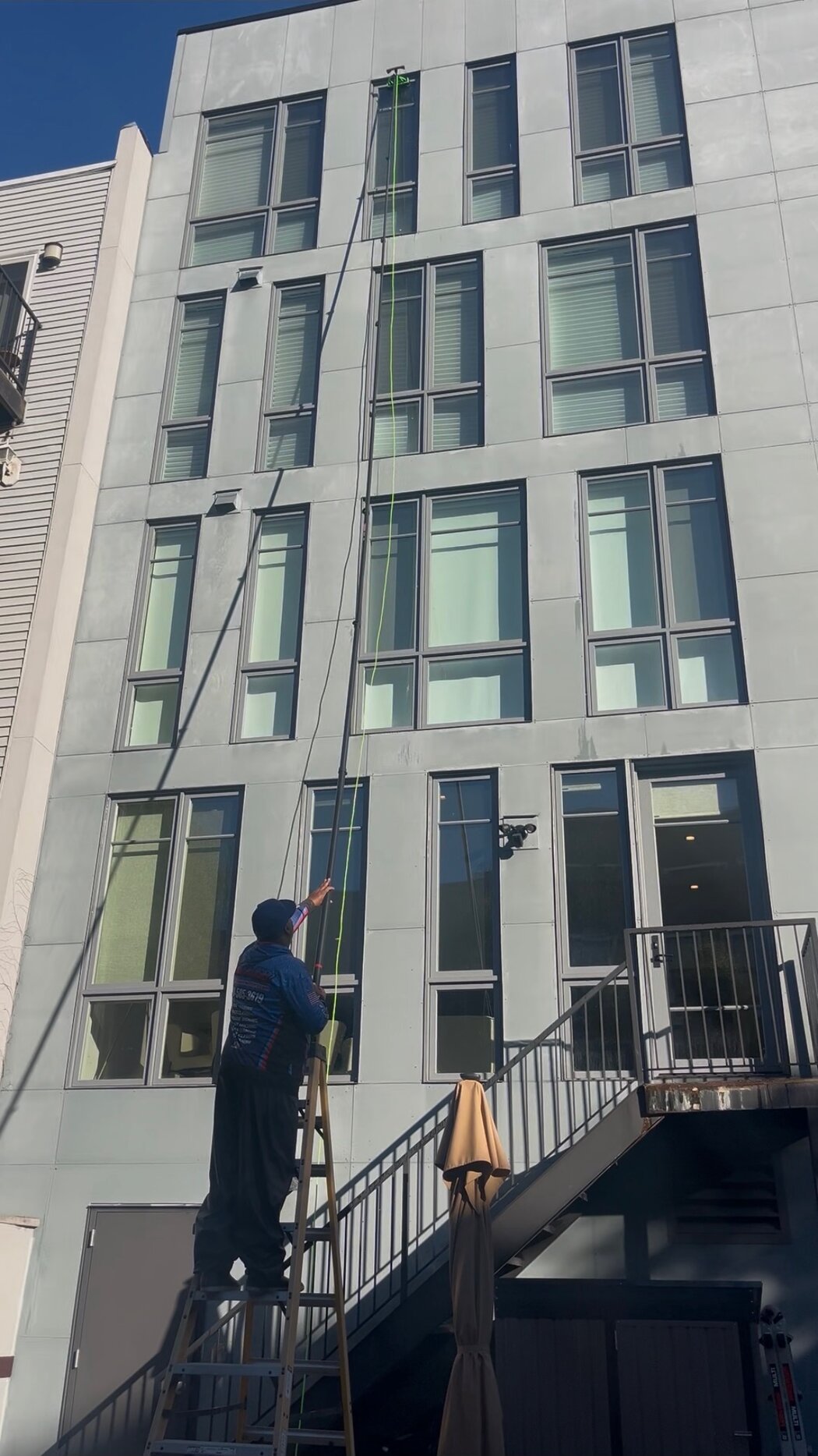 Crew washing five story condo windows with a water fed pole