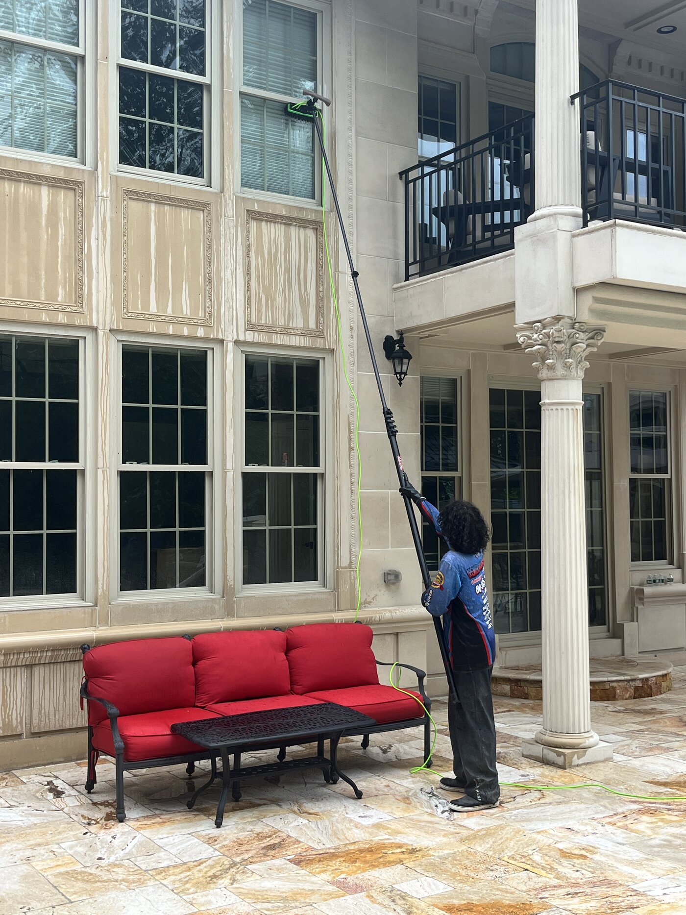 Crew member reaching second story limestone with a water fed pole