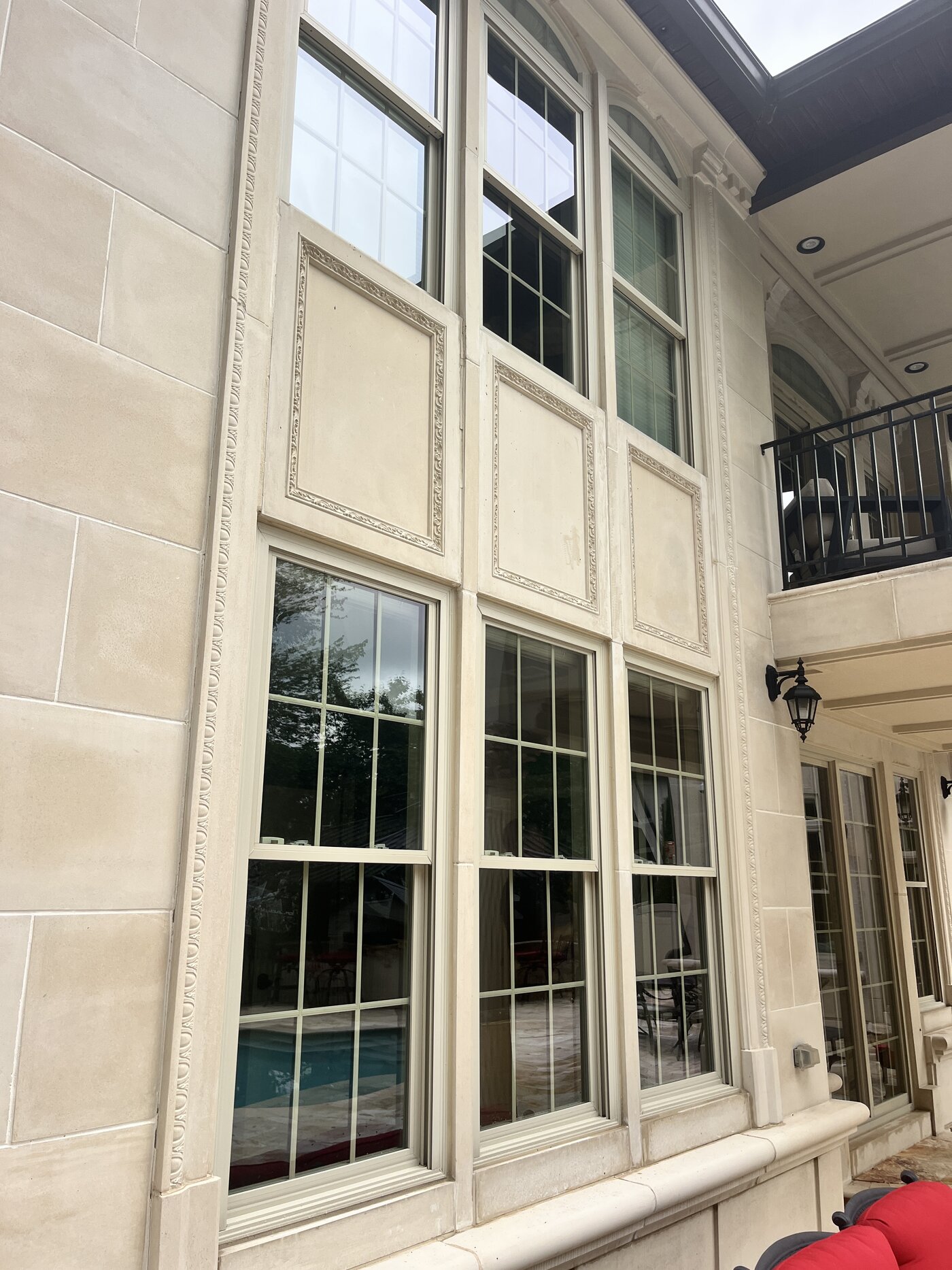 Tan streaking running down cast limestone panels before soft washing
