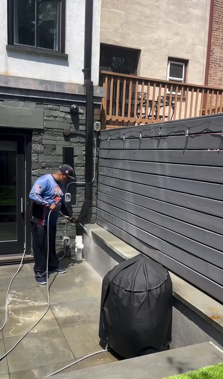A technician detailing the stacked stone base and rear door surround with a hose