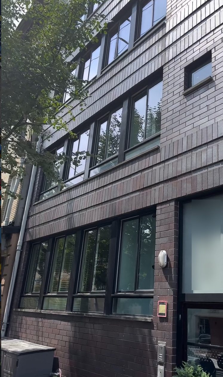 The dark brick street facade of the Hoboken condo building with its rows of black framed windows