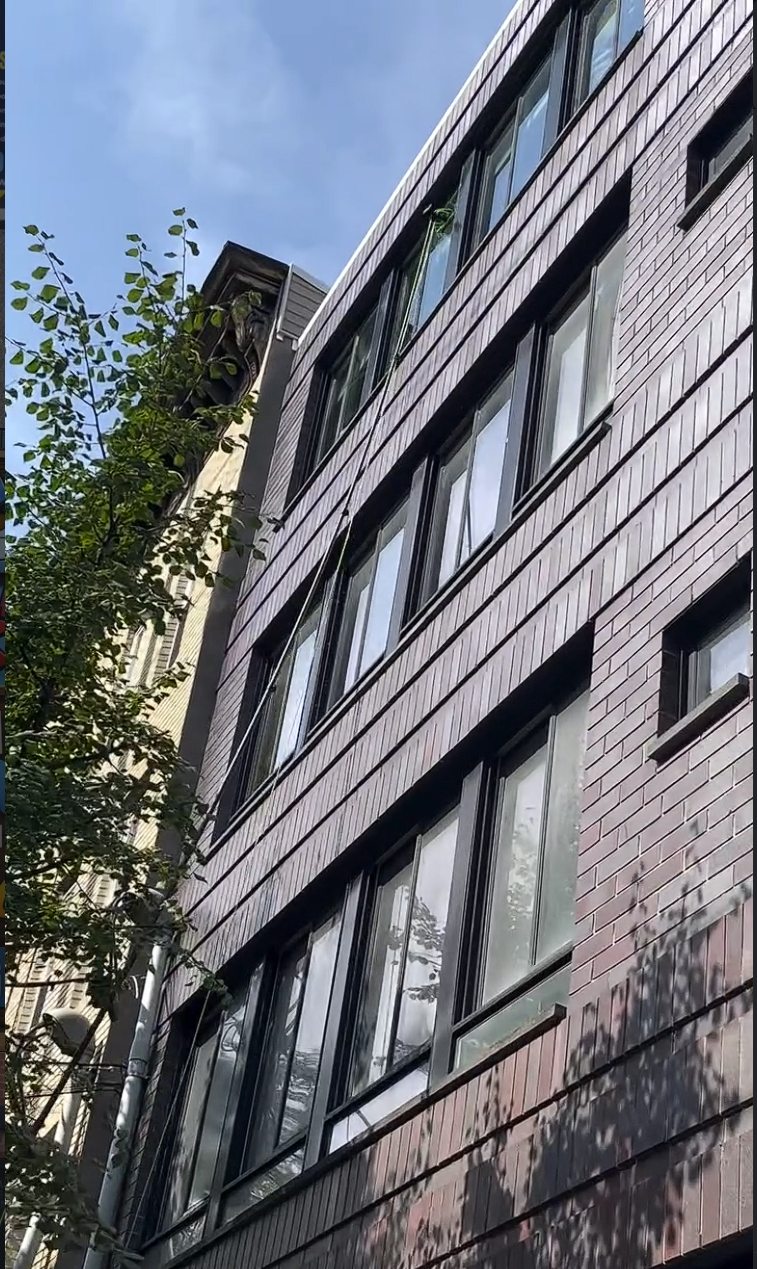 A water fed pole brush working the upper floor windows of the brick facade