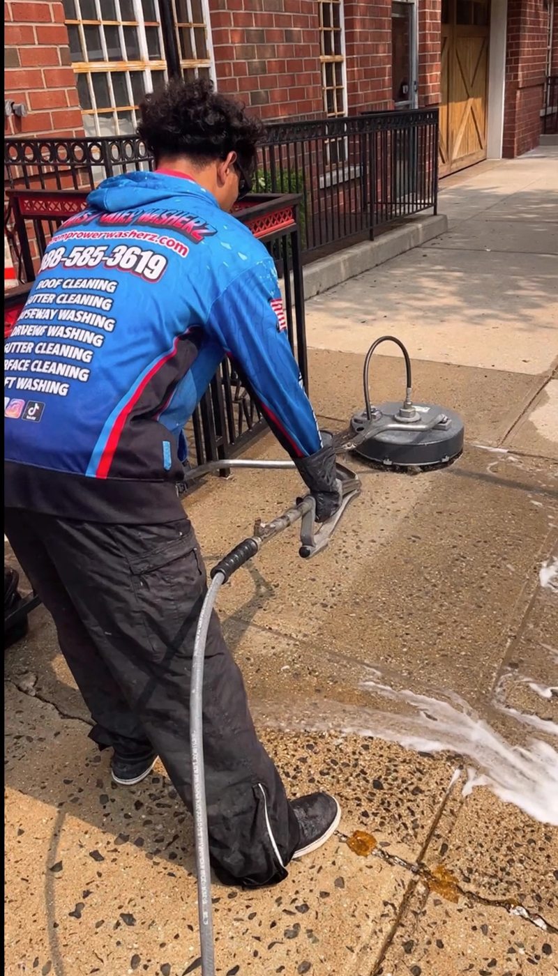 A Premier Power Washerz technician guiding a surface cleaner across the sidewalk outside the restaurant