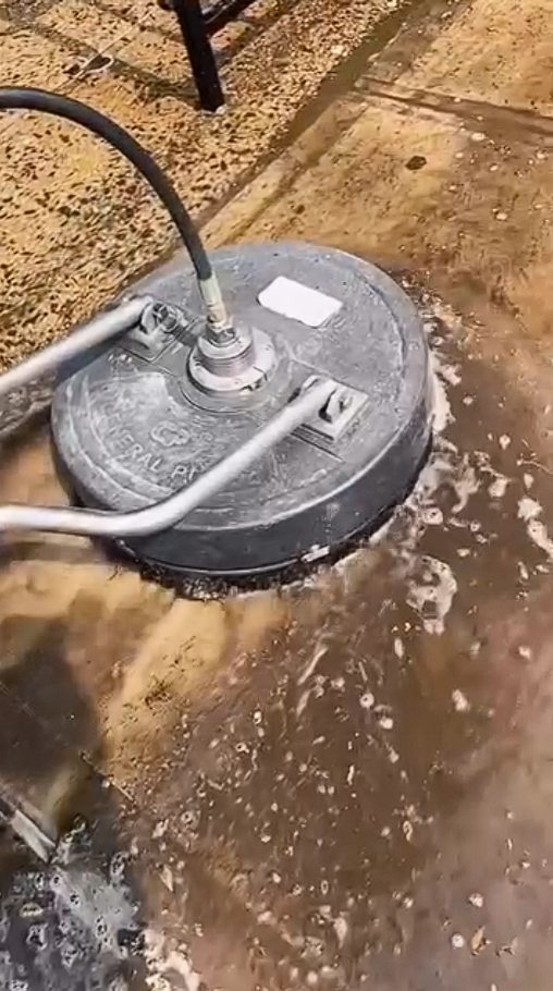 A close view of the surface cleaner running across oil stained concrete with suds working