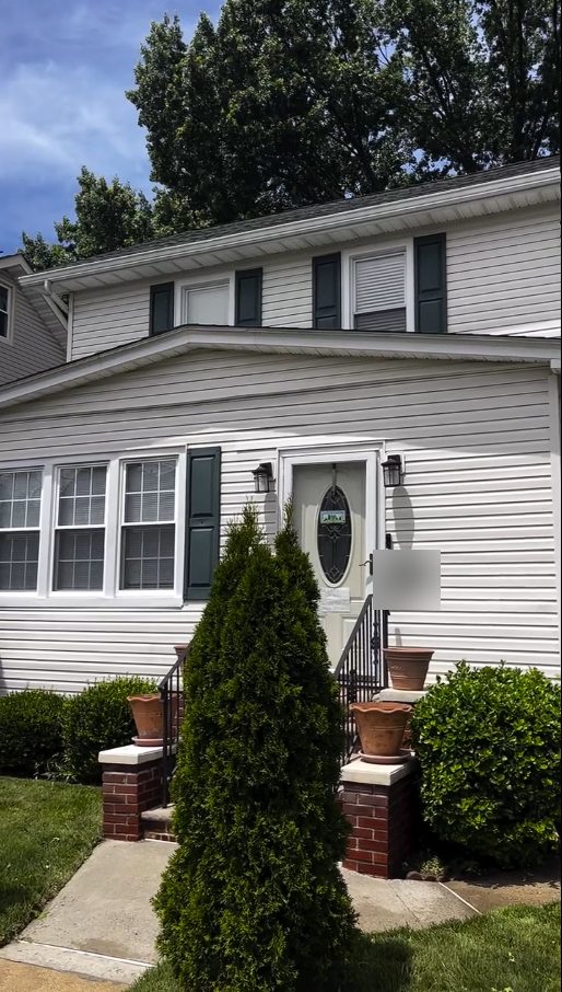 The front of a white sided Irvington NJ colonial with dark green shutters after its house wash