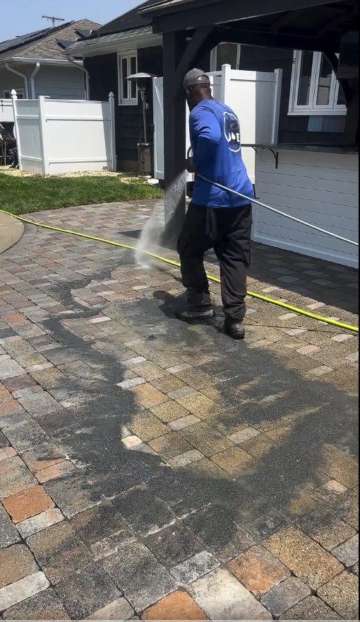 A technician washing the paver patio beside the outdoor bar area