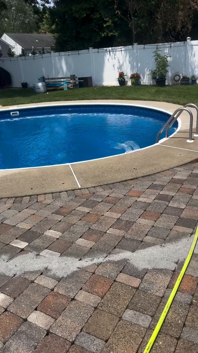 Fresh joint sand spread in a band across the pool deck pavers before sweeping